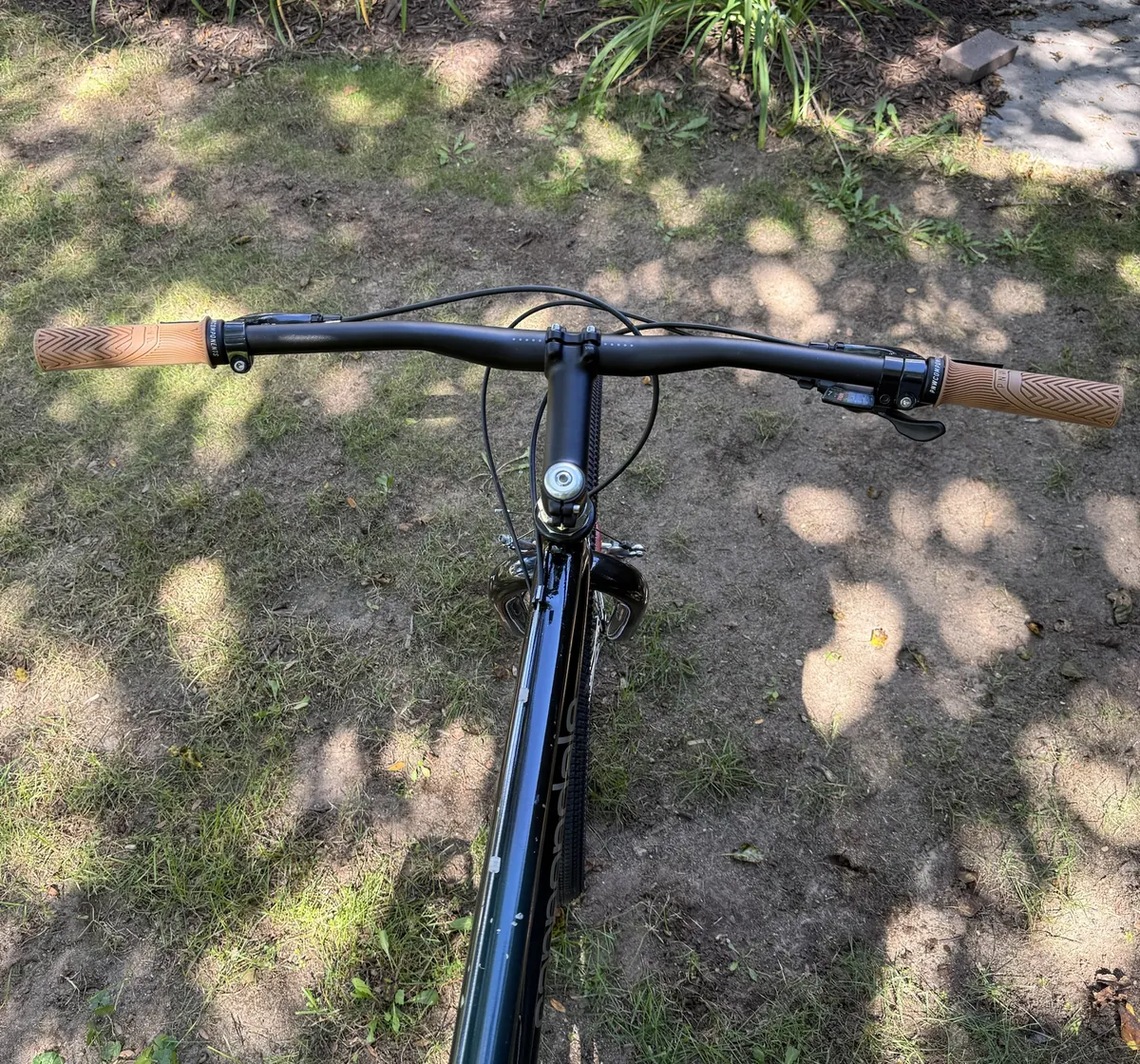 View from the saddle of the wide black handlebar with tan grips.