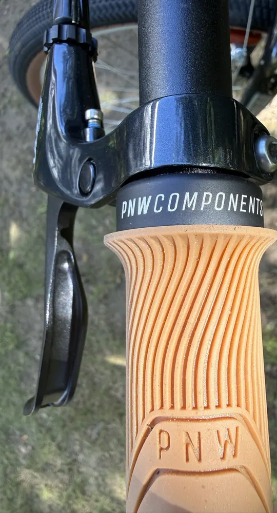 Tan PNW Loam grip with a black PNW Components lock ring next to a Shimano Sora lever.