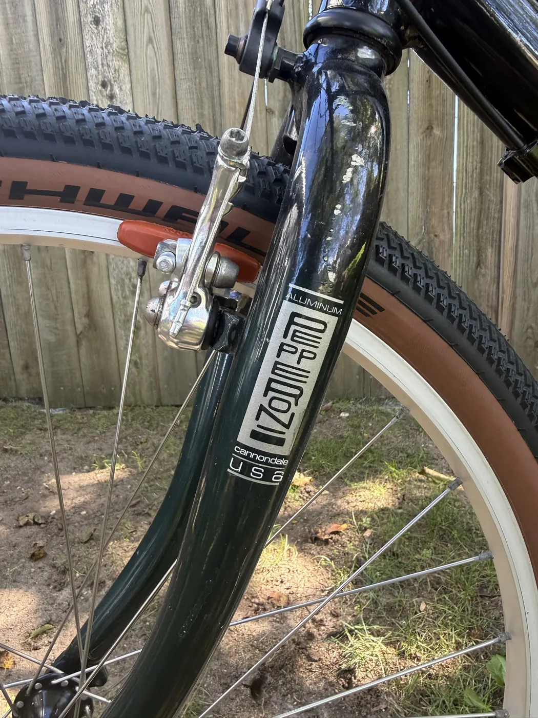 Close-up of the fork blade decal reading Aluminum, Pepperoni, cannondale USA, beside a CODA cantilever brake with a salmon Kool-Stop pad.